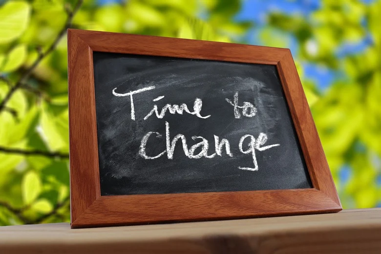 Kreidetafel mit dem Text »Time to change« und im Hintergrund ist Natur zu sehen.