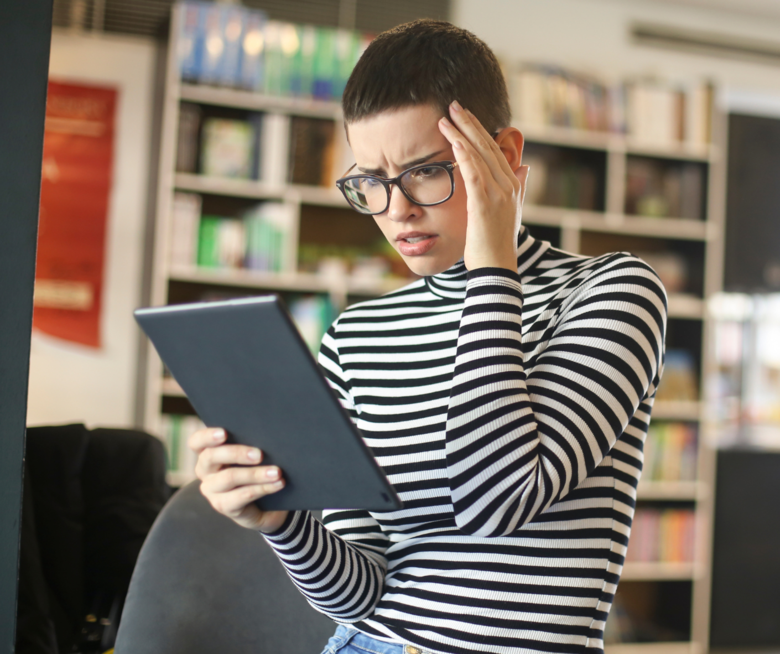 Eine Frau, die ganz erschrocken auf ihr Tablet schaut.