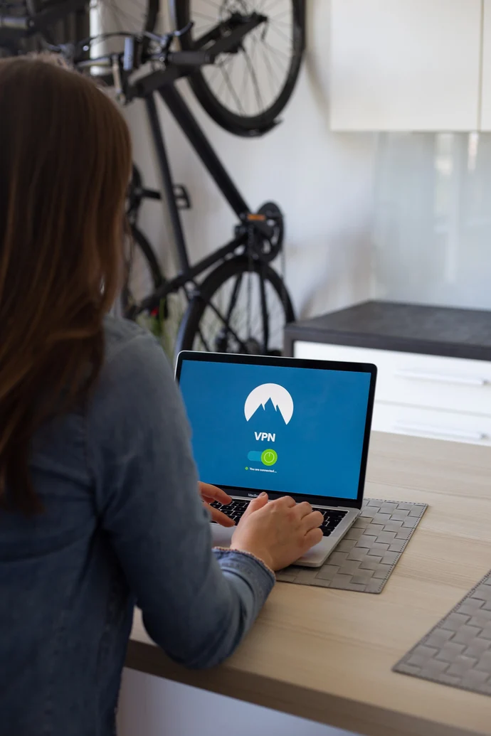 Frau sitzt mit Laptop an einem Tisch und loggt sich in einen sicheren VPN Tunnel ein