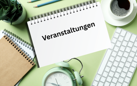 Ein Schreibtisch von oben fotografiert. Zusehen sind eine Tastatur, ein Wecker, Stifte und Blöcke. Auf einem Block steht Veranstaltungen