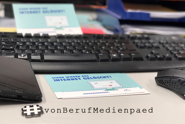 Bild vom Schreibtisch mit Tastatur, Maus, Handy und Postkarte